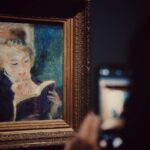 Kvinde sidder og læser i en bog i en udstillingssal på et kunstmuseum